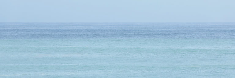 Blue still ocean with a horizon and blue sky