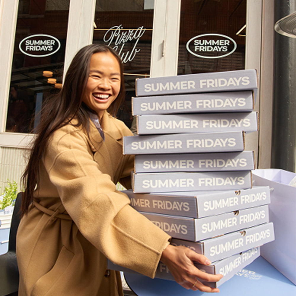 Woman holding a stack of 'Summer Fridays' boxes outside a store.