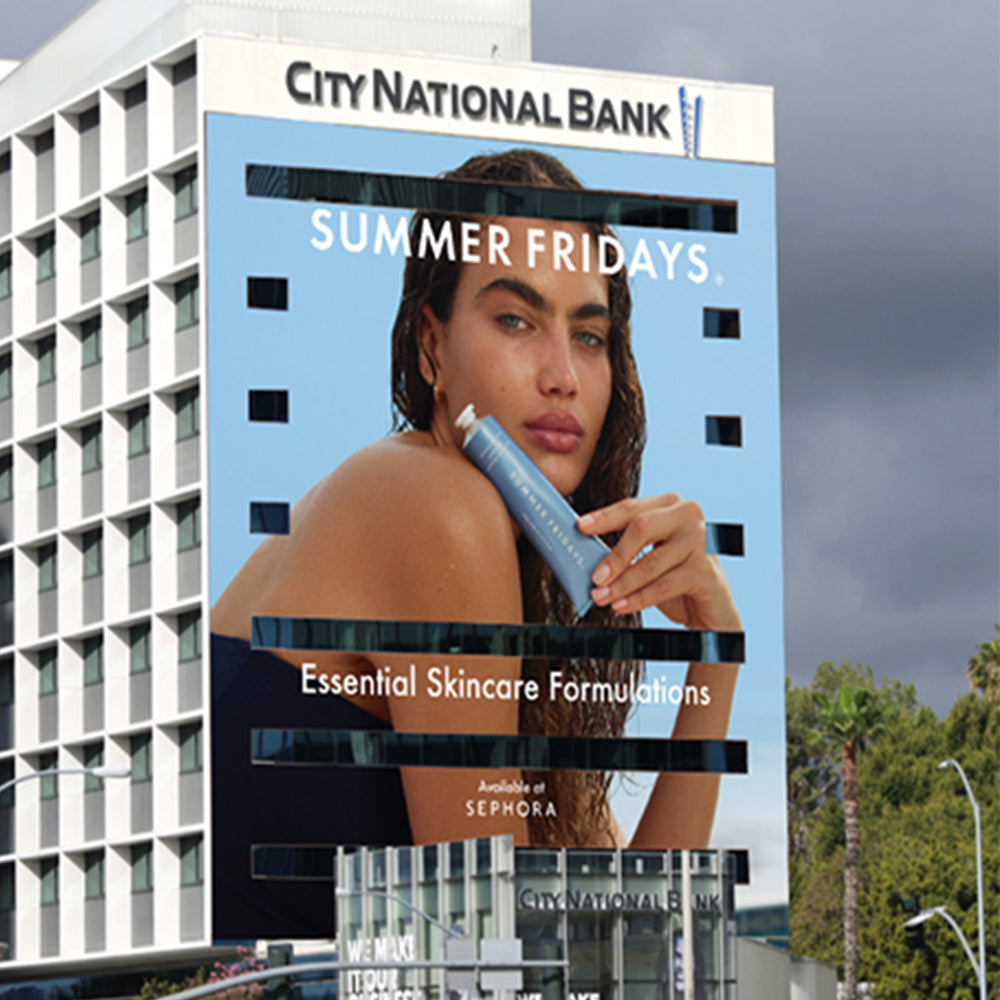 Large outdoor advertisement for City National Bank featuring a woman with skincare product on a building.