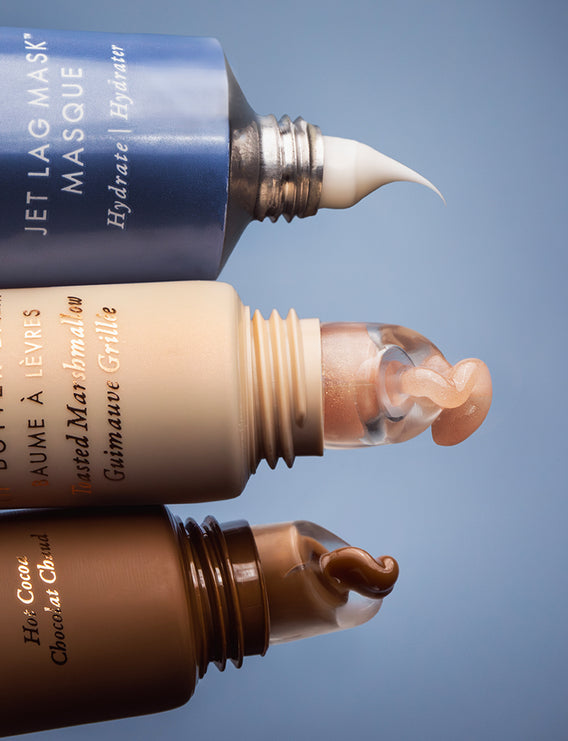 Three cosmetic bottles with applicators on a gradient blue background