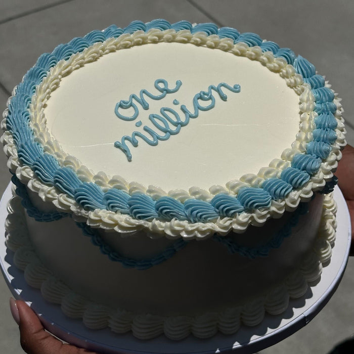 Cake with 'one million' written on it, held by a person.