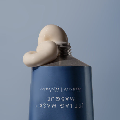 Close-up of a blue bottle with cream being applied on a light blue background