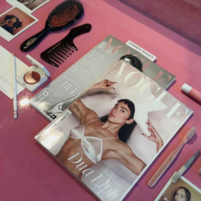 Vogue magazine with beauty products on a pink surface