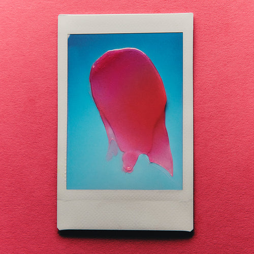 Framed photograph of a pink lip balm swatch on a pink background