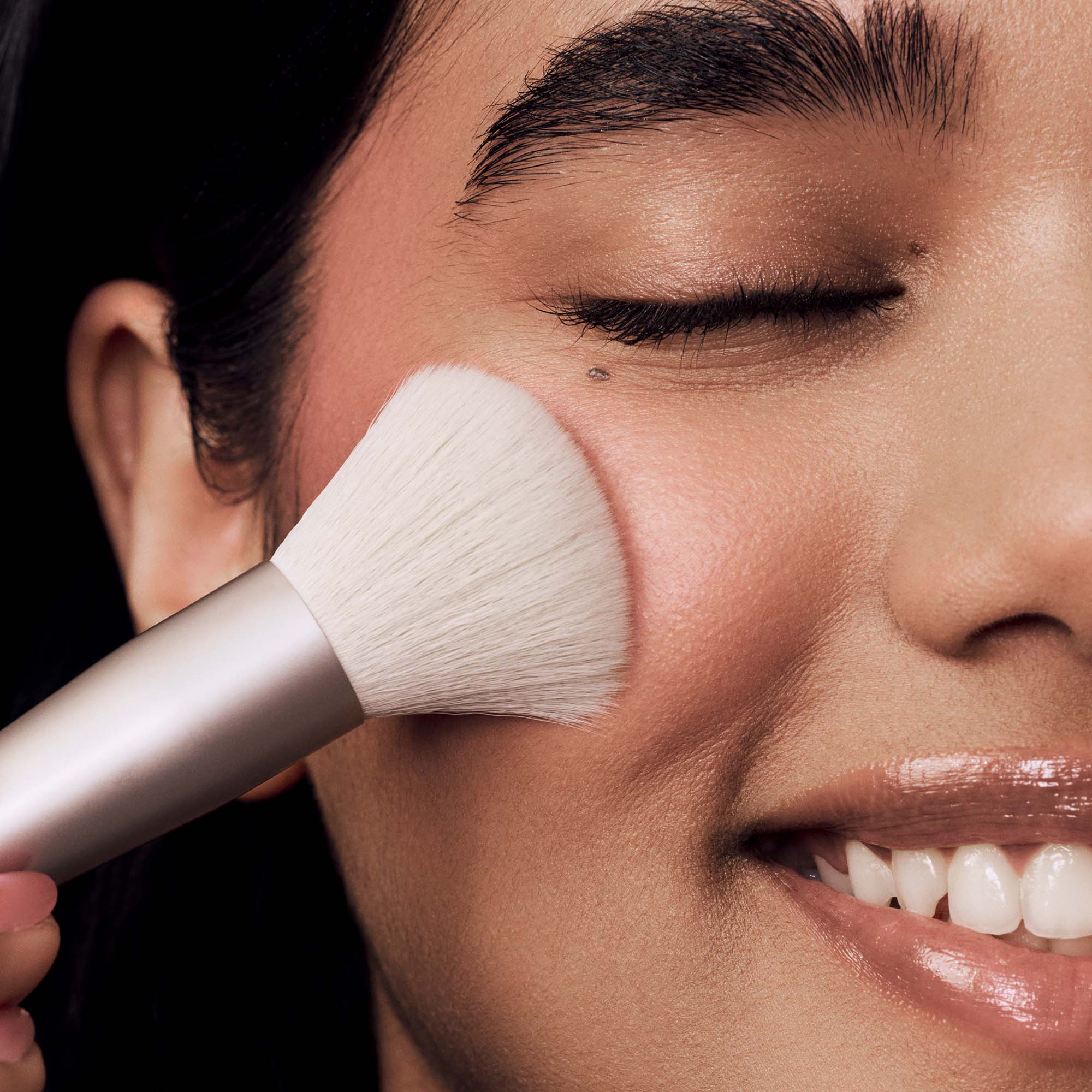 Person applying makeup with a brush on their face