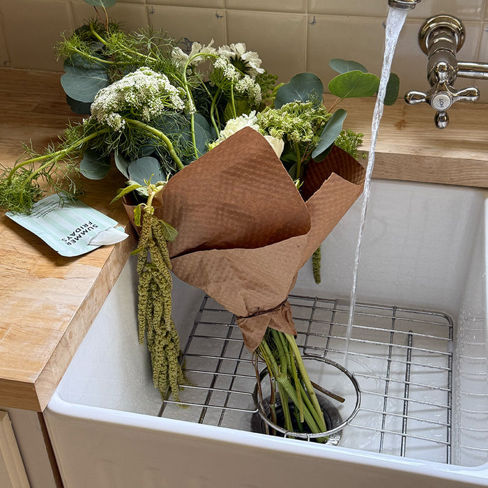 Bouquet of flowers in a sink with water flowing from a faucet