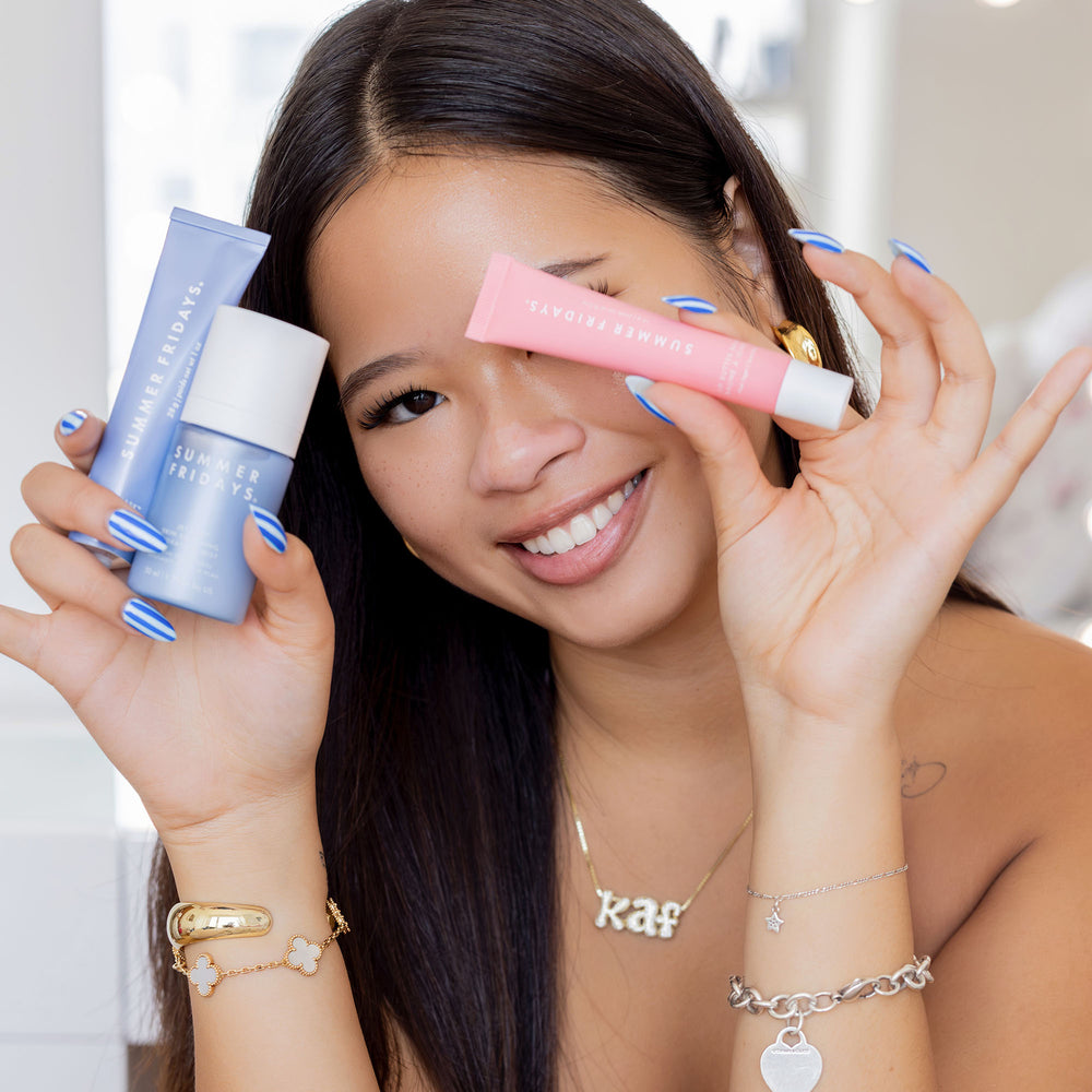 Woman holding skincare products with a blurred background
