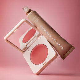 Makeup products including a blush and a tube of cream on a pink background with 'Summer Fridays' branding.