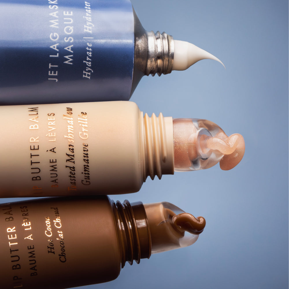 Three lip balm tubes with visible product being squeezed against a blue background