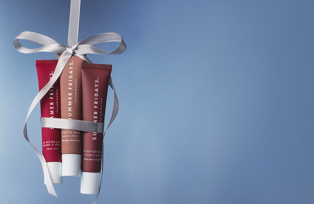 Three lip balm tubes with a white ribbon on a blue background